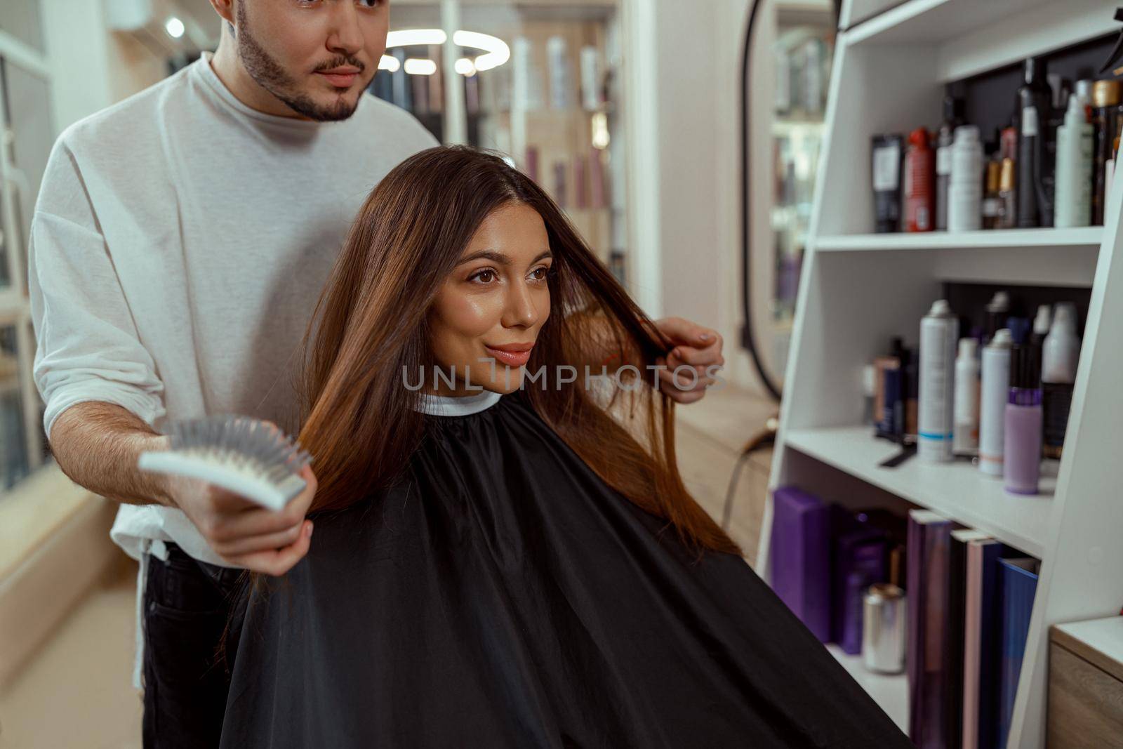 Woman looking at herself in mirror, pleased with a hairstyle at beauty salon by Yaroslav_astakhov