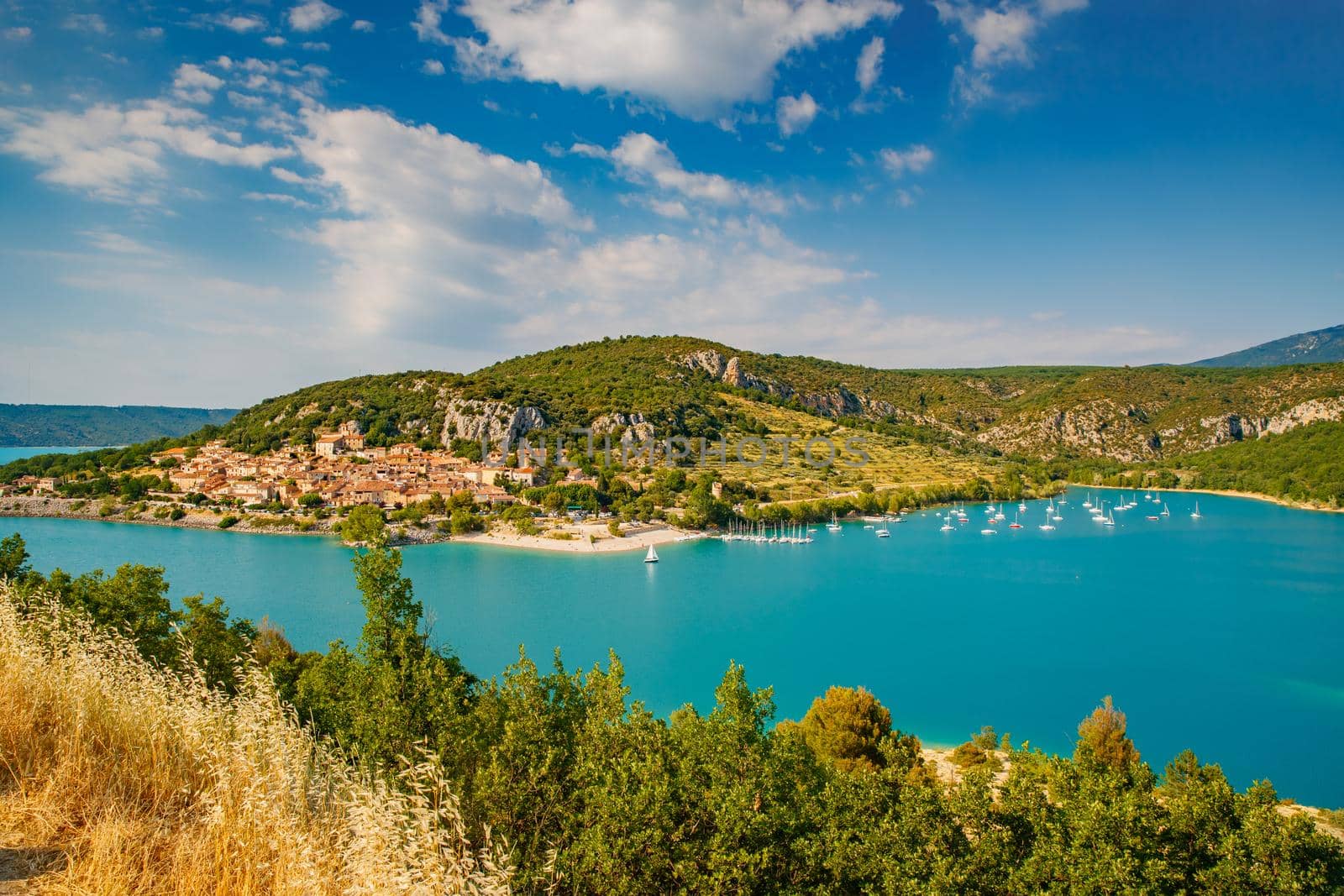 The city on the bank of the artificial lake in France, Provence, lake Saint Cross, gorge Verdone, azure water of the lake and slopes of mountains on a background, small boats, vacations place. High quality photo