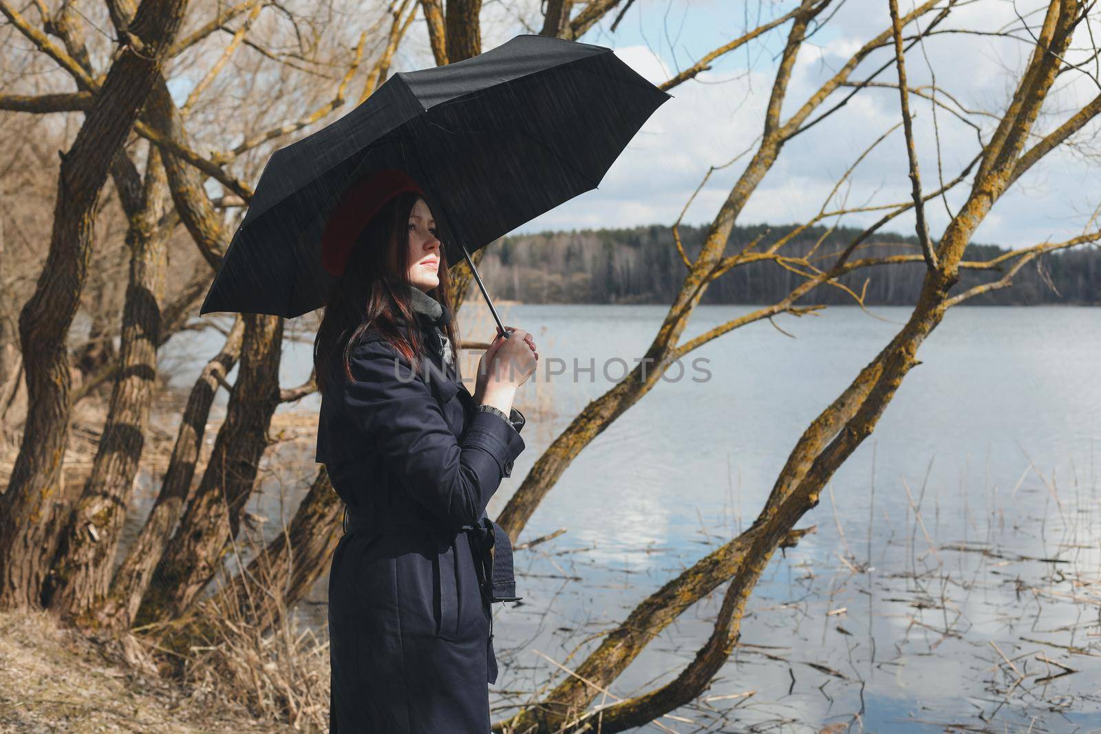 Portrait of a young nice woman with black umbrella on the beach outdoors