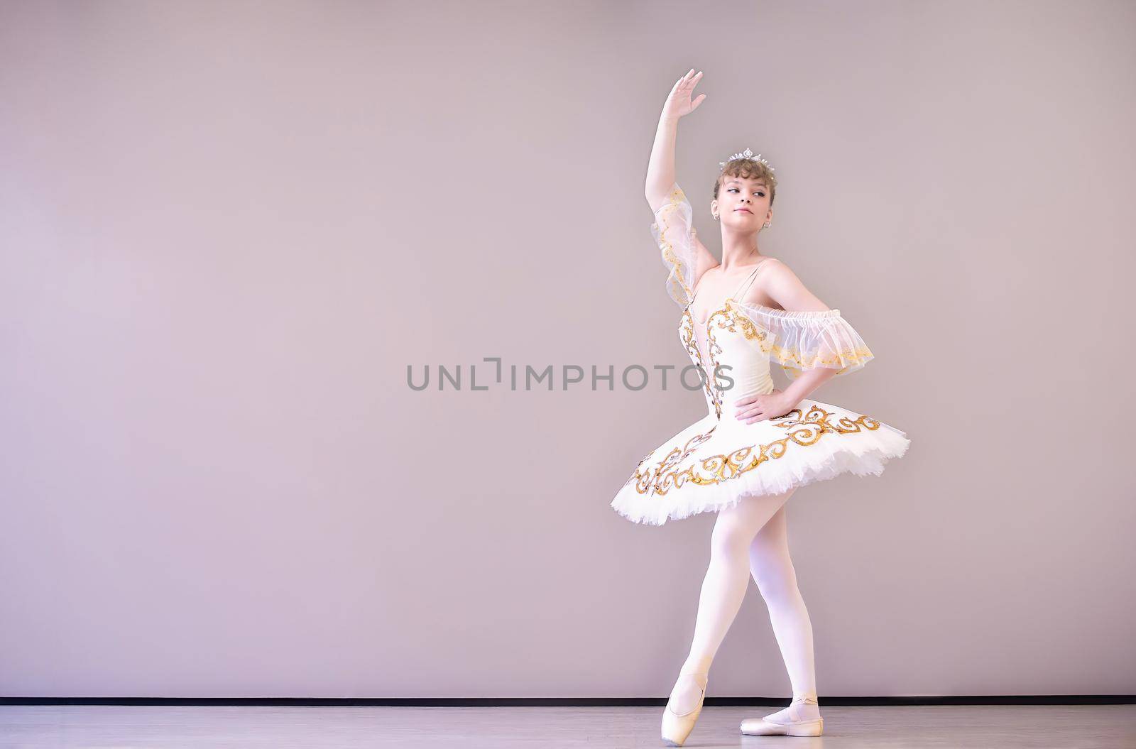 young Classical Ballet dancer in studio is standing on tiptoe.young beautiful graceful caucasian ballerina practice ballet positions in tutu skirt of white swan