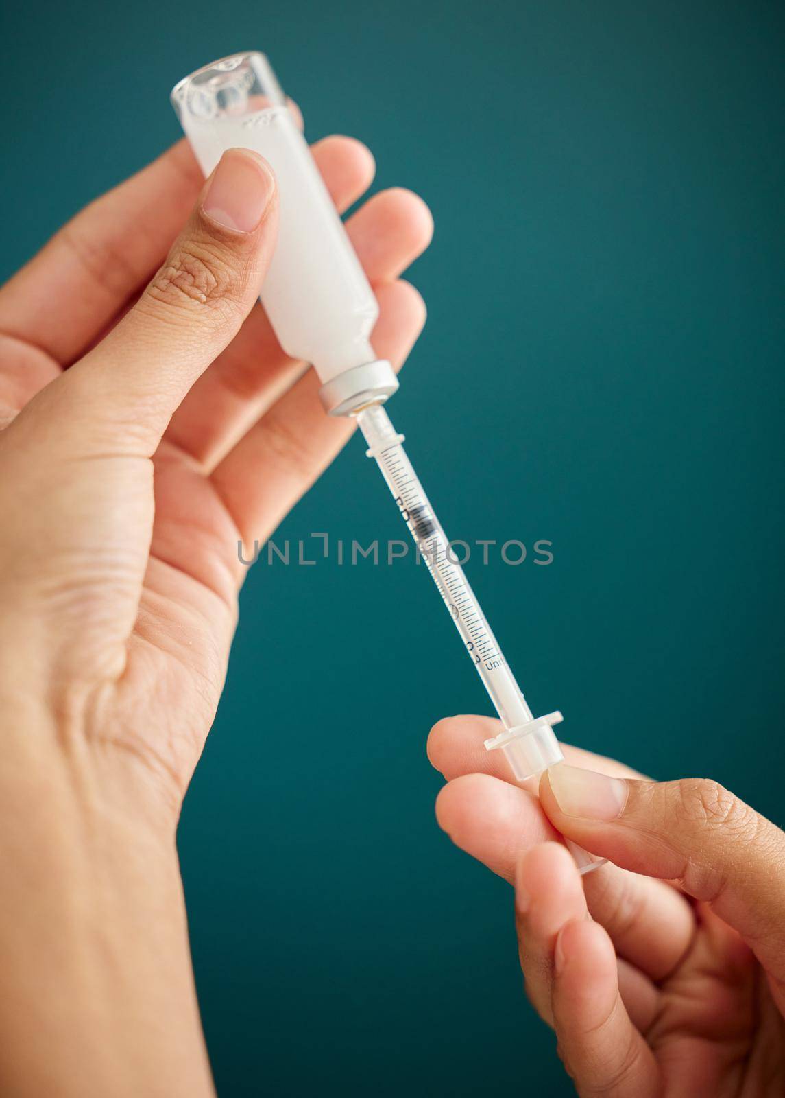 The perfect dose of insulin. Cropped shot of an unrecognizable woman drawing a dose of insulin into a syringe at home. by YuriArcurs