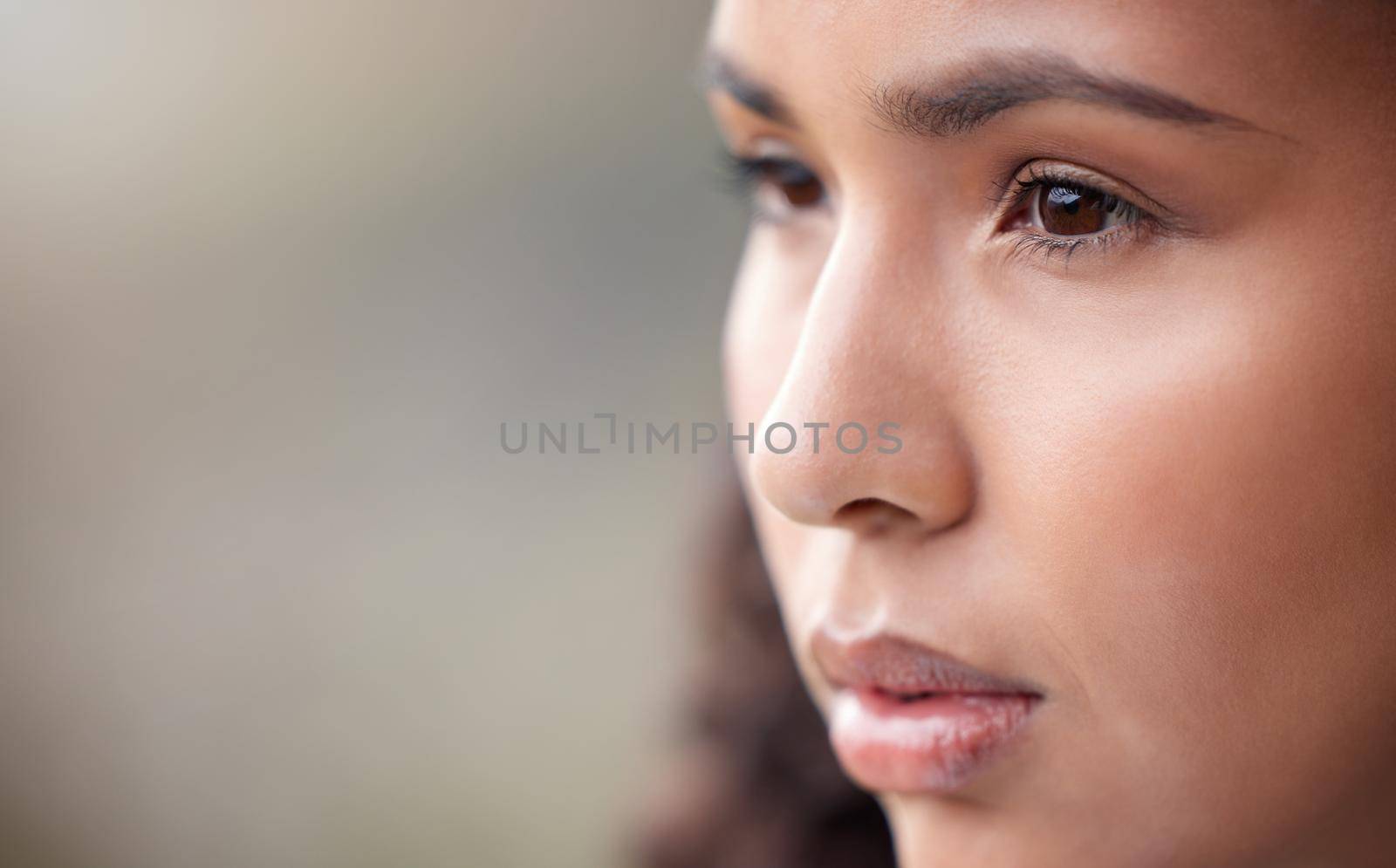 Closeup shot of a beautiful young woman looking thoughtful while standing outside.