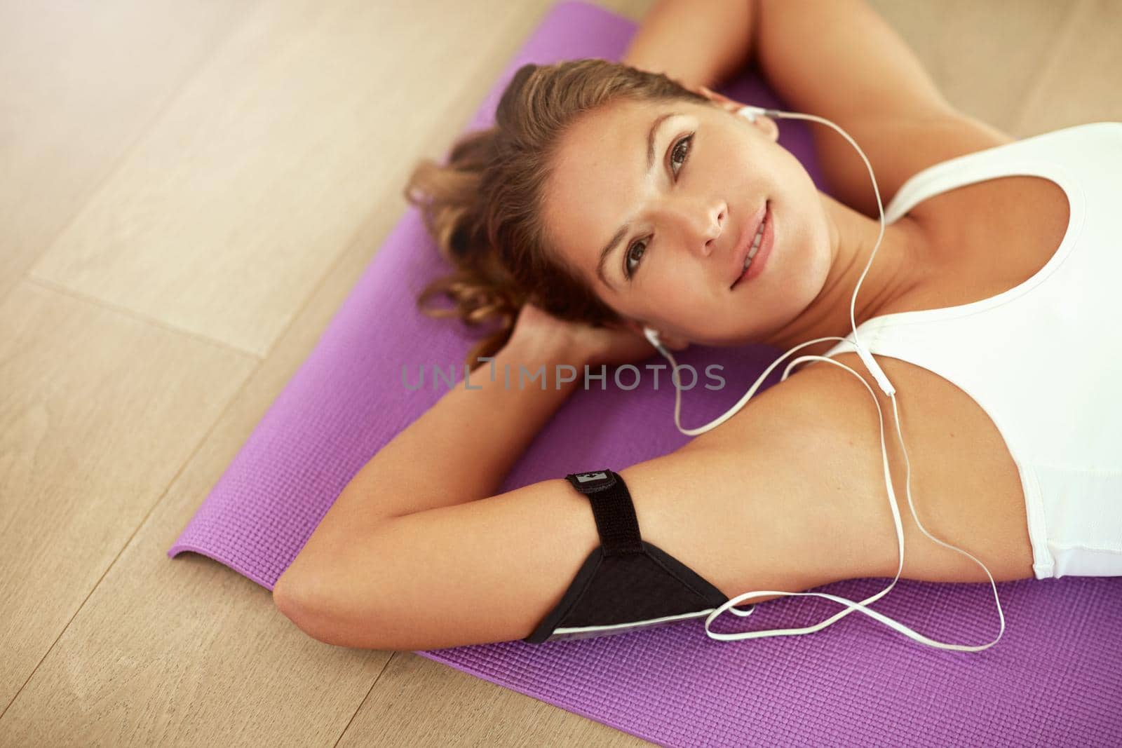 Cropped shot of a sporty young woman listening to music while lying on an exercise mat.