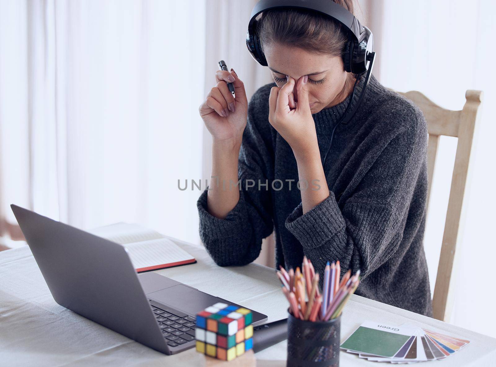 Self-care is essential to combating burnout. Shot of a young getting a headache while teaching an online lesson with her laptop at home. by YuriArcurs