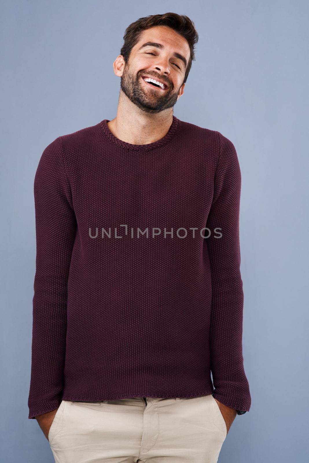 Studio shot of a handsome and happy young man posing against a gray background.