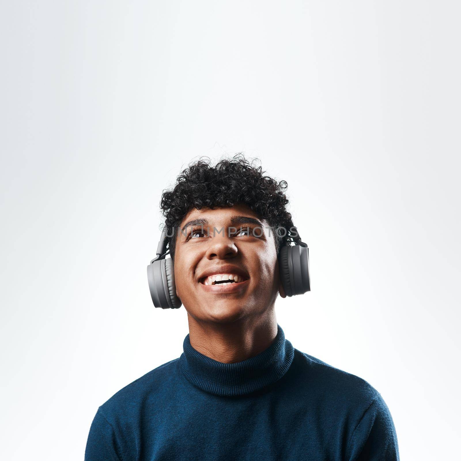Studio shot of a young man using headphones against a grey background.