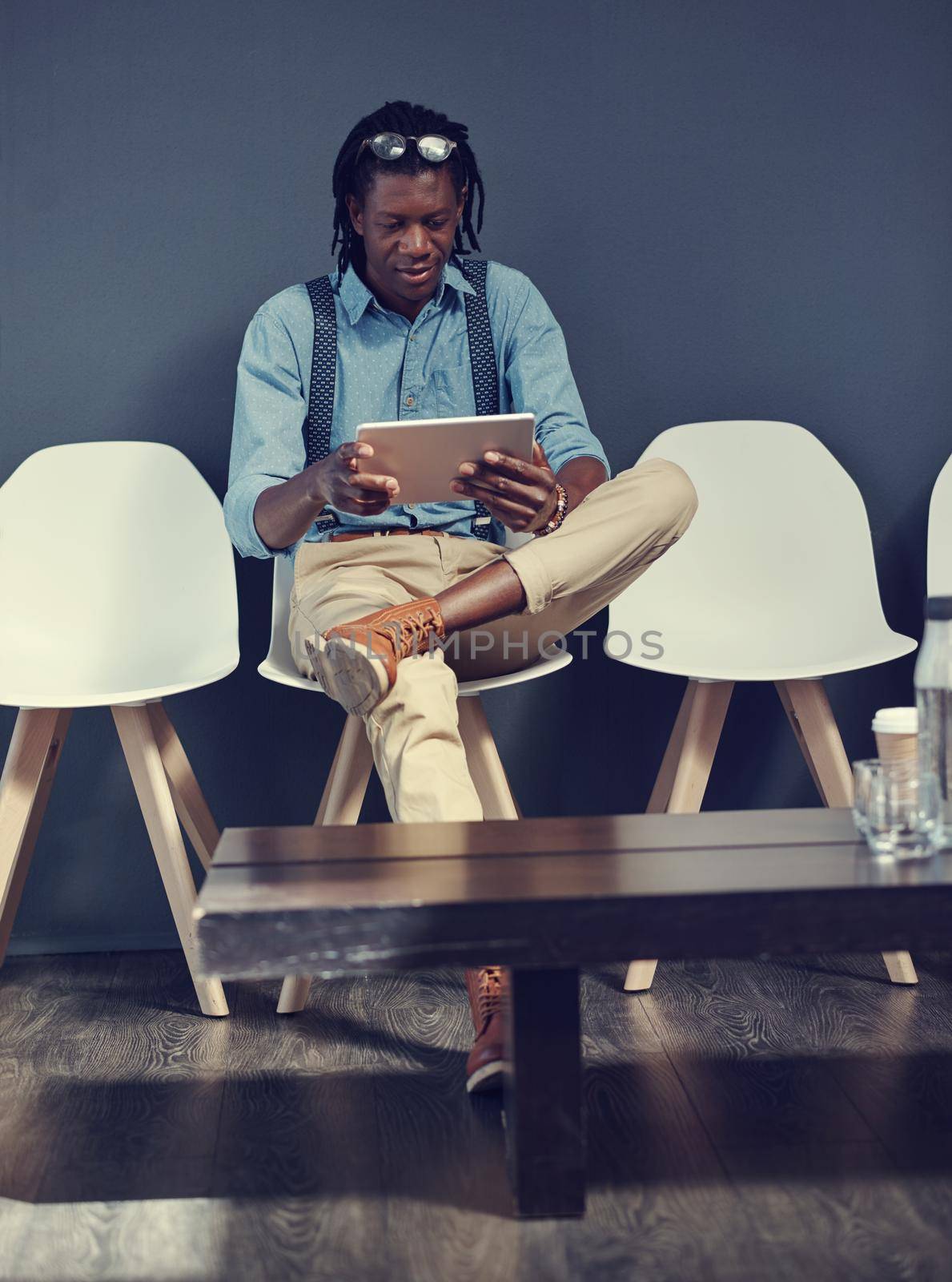 Shot of a young businessman using a tablet while waiting for an interview.