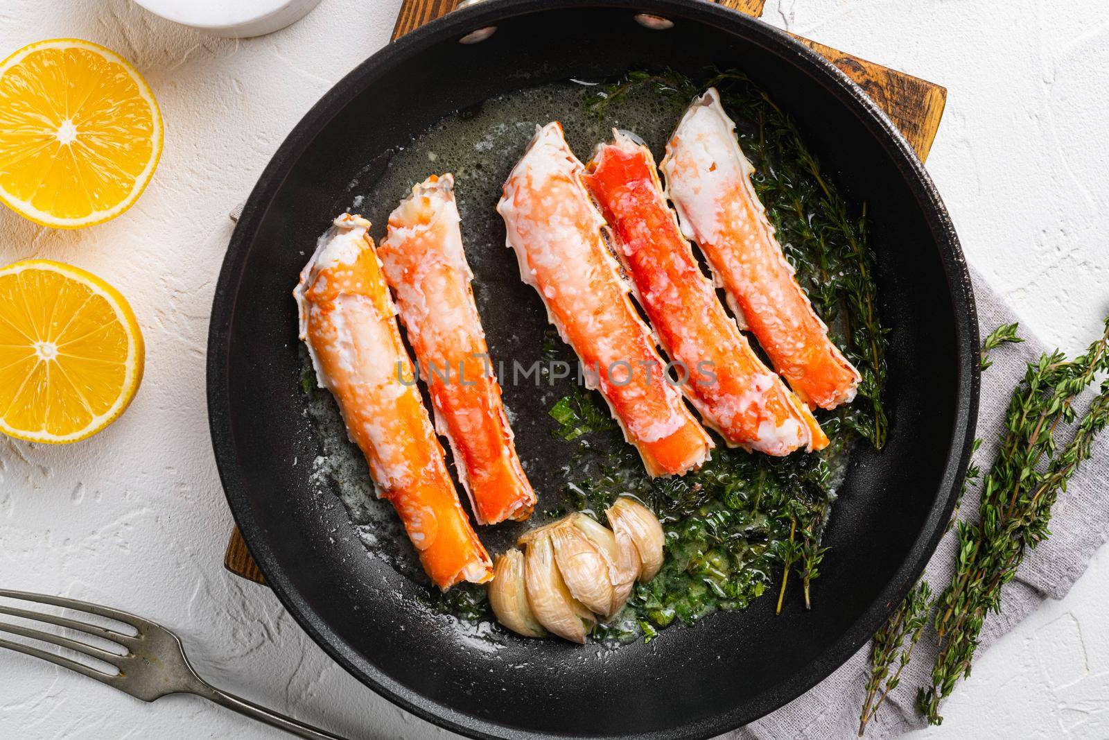 Cooked King Crab legs meat, in cast iron frying pan, on white stone table background, top view flat lay by Ilianesolenyi