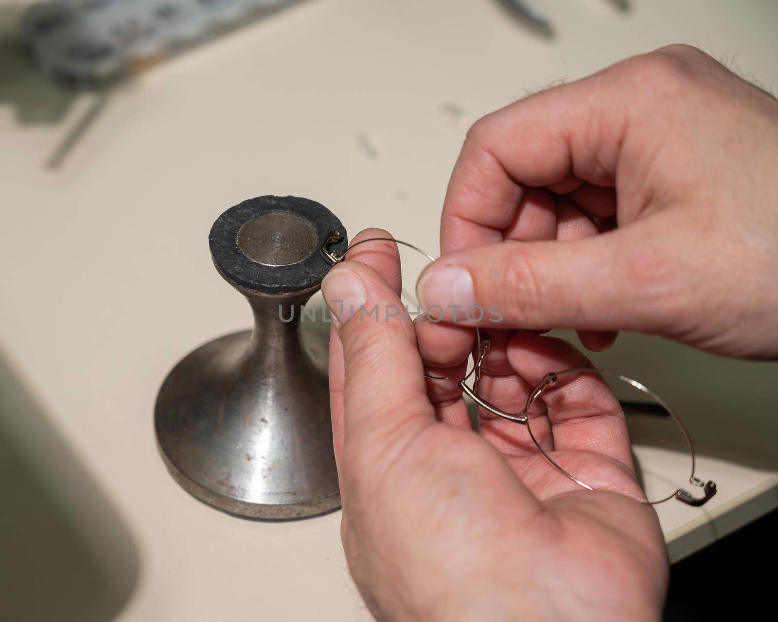 Optical technician fixing glasses. Close-up of male hands with screwdriver and goggles frame