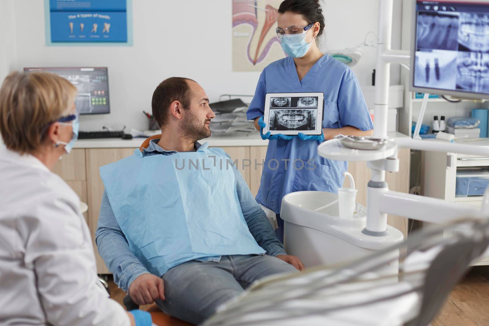 Dentist assistant with face mask holding tabet computer by DCStudio