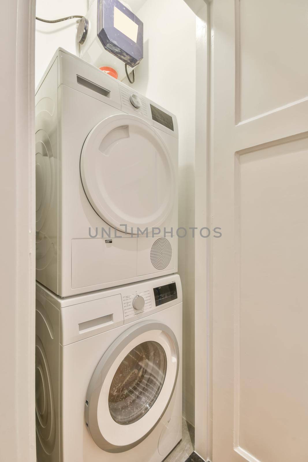 A small laundry corner with a washing machine and dryer in white tones in a modern house