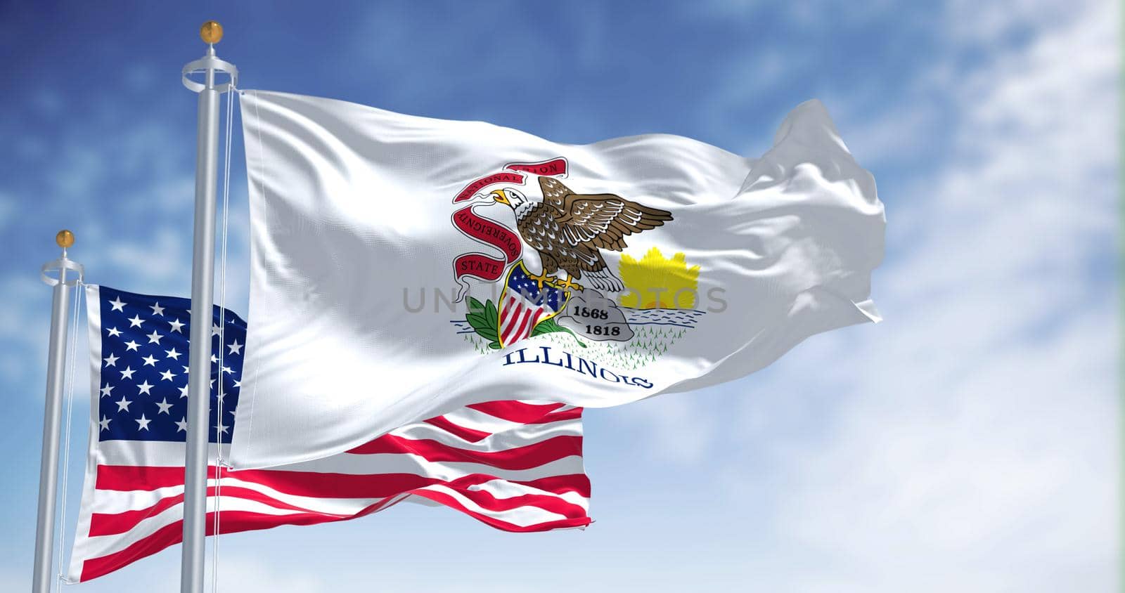 The Illinois state flag waving along with the national flag of the United States of America. In the background there is a clear sky. Illinois is a state in the Midwestern region of the United States