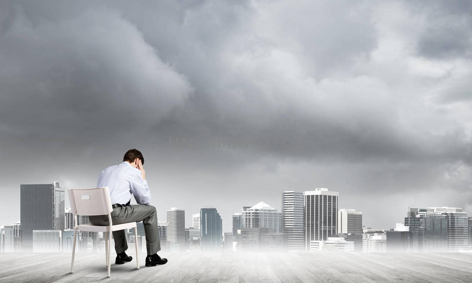 Businessman sitting on an office chair with his back, thinking and holding his head