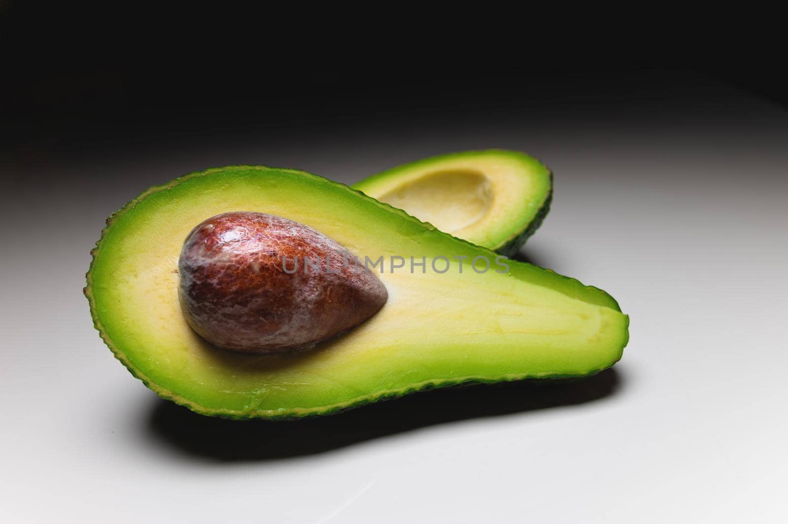 Avocado on old wooden table.Halfs on wooden bowl. Fruits healthy food concept