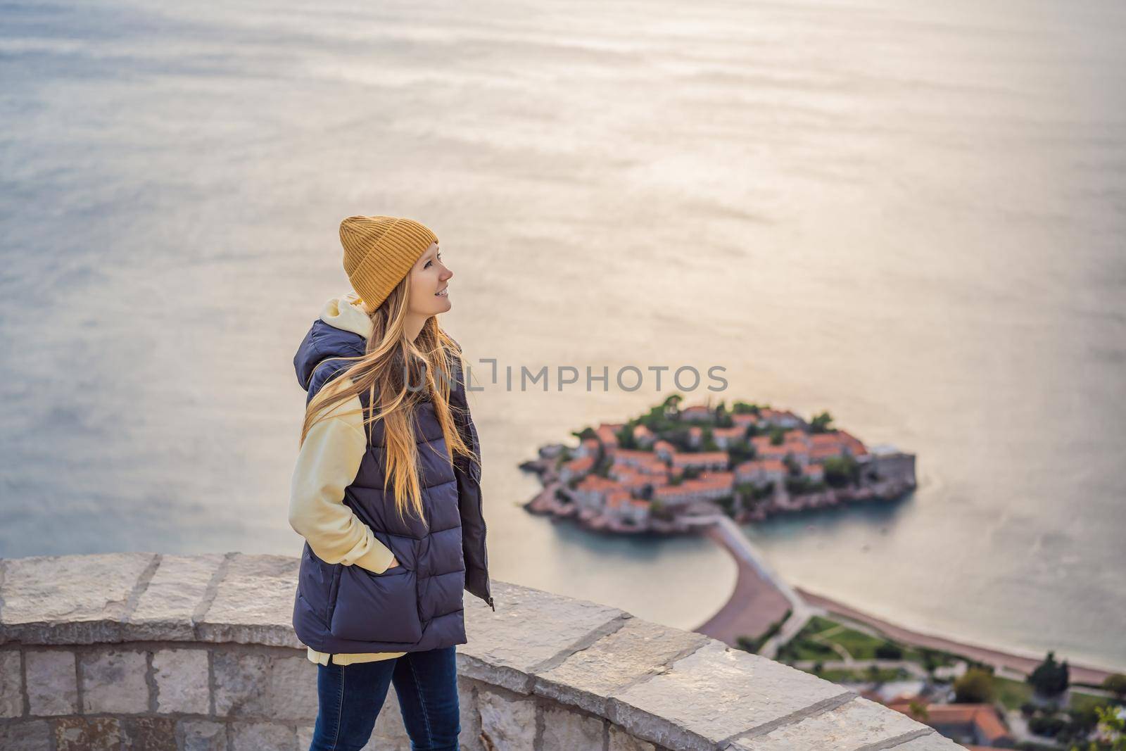 Woman tourist on background of beautiful view of the island of St. Stephen, Sveti Stefan on the Budva Riviera, Budva, Montenegro. Travel to Montenegro concept.