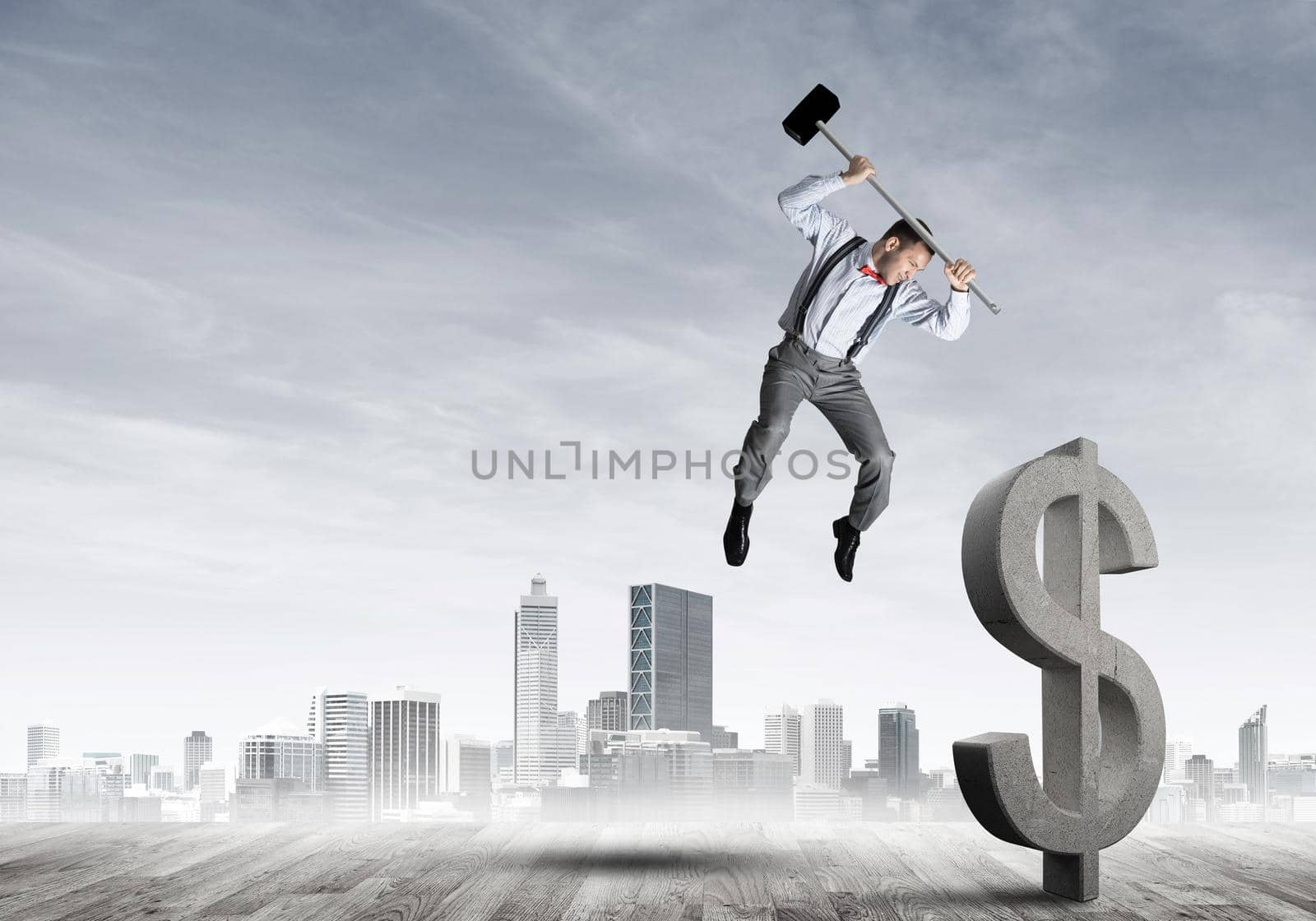 Determined banker man against modern cityscape breaking dollar concrete figure by adam121