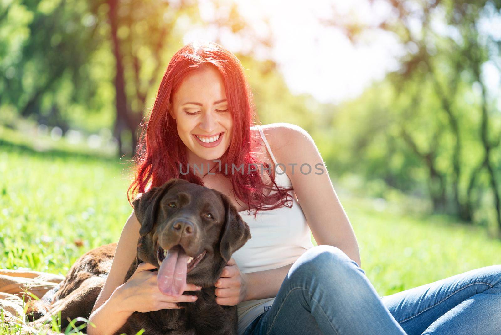 Young attractive woman hugs her dog in the park. by adam121