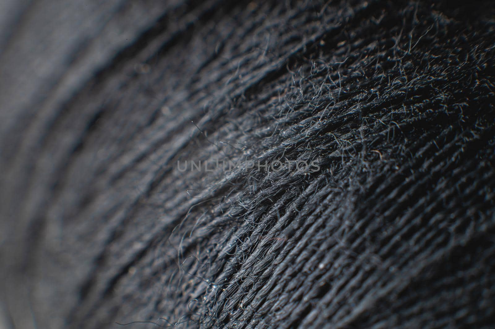 Dark gray spool of thread at extremely high magnification and shallow depth of field. Textile background by yanik88