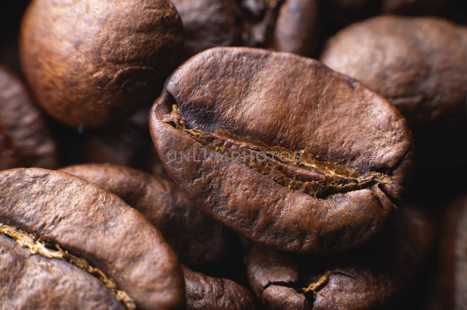 Close up extreme macro group of roasted brown or black coffee beans background in shallow depth of field. Enchanting coffee aroma.