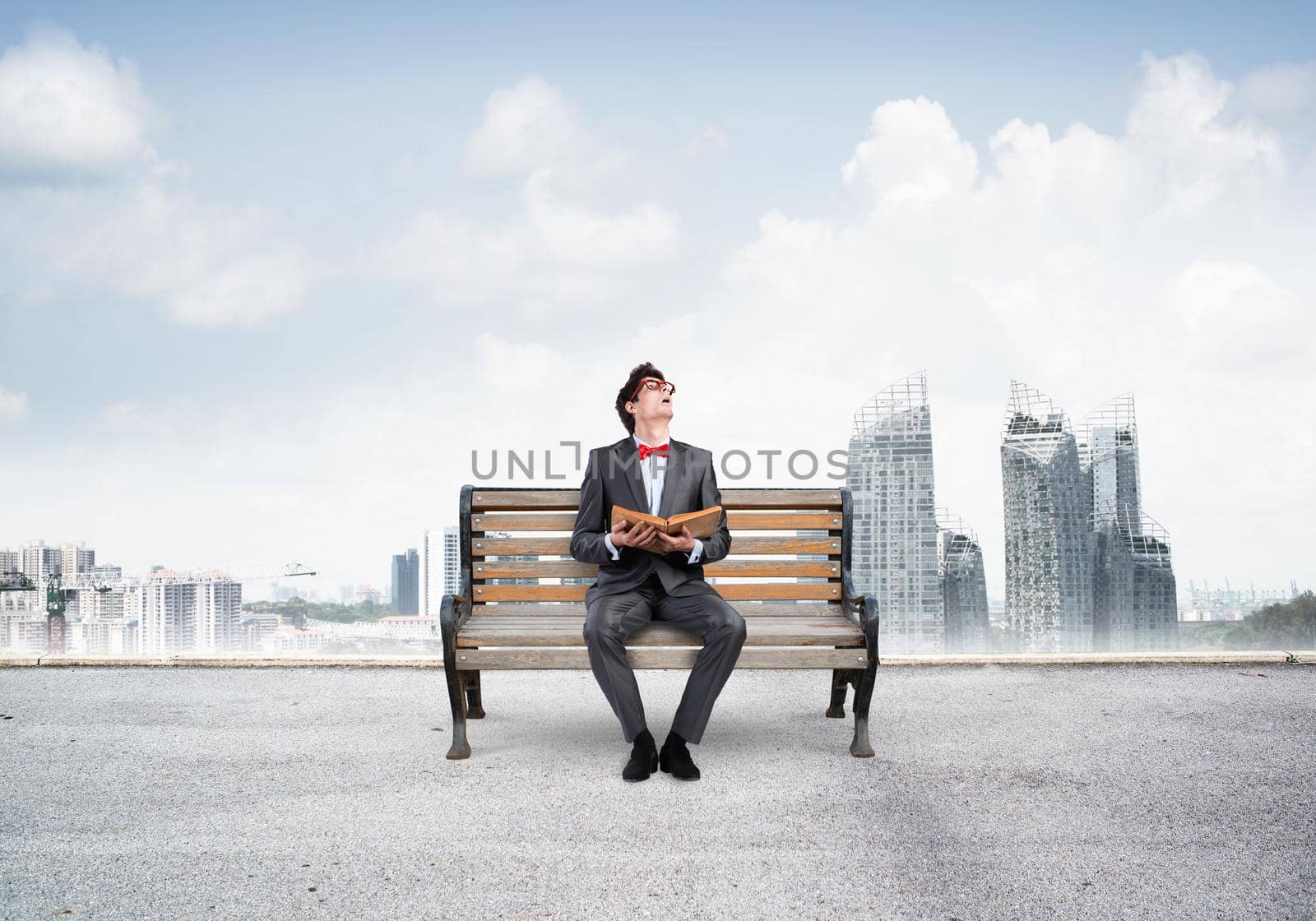 Student sits on a bench, holding a book. Traditional education concept