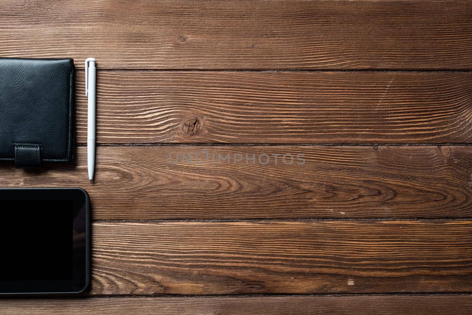 Still life of office workspace with supplies. Flat lay old hardwood desk with black leather wallet and tablet computer. Online shopping and payment. Creativity and innovation concept with copy space