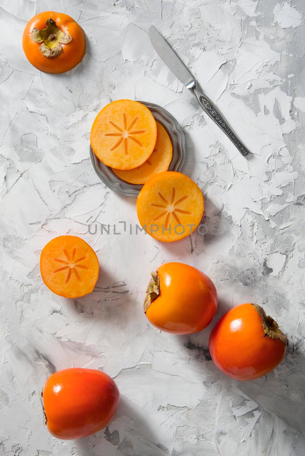 Persimmon slices lie on a gray background in the form of a hexagonal tile, colorful food, flatley fruits. High quality photo