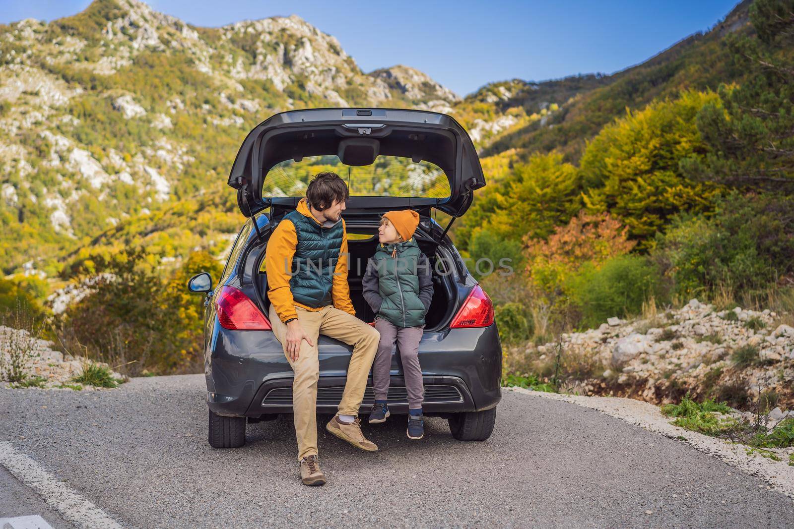 Dad and son are resting on the side of the road on a road trip. Road trip with children concept.