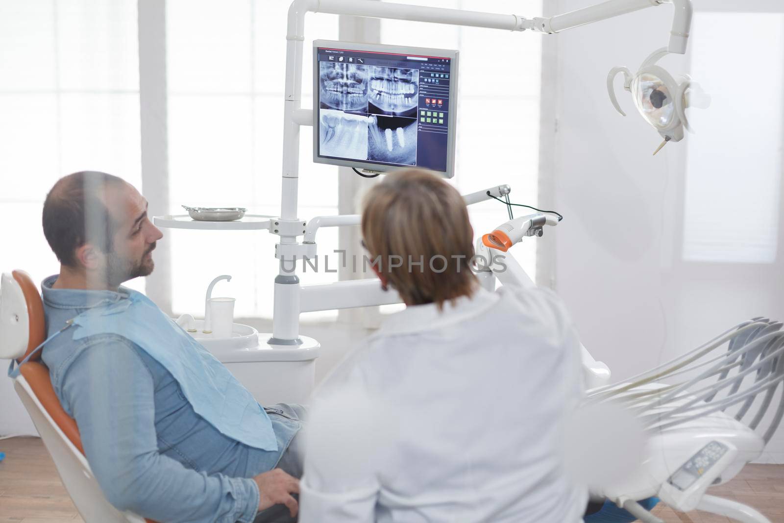Patient with toothache sitting on dental chair looking at teeth radiography discussing dentistry treatment with stomatologist doctor during medical consultation in dental office. stomatology Concept