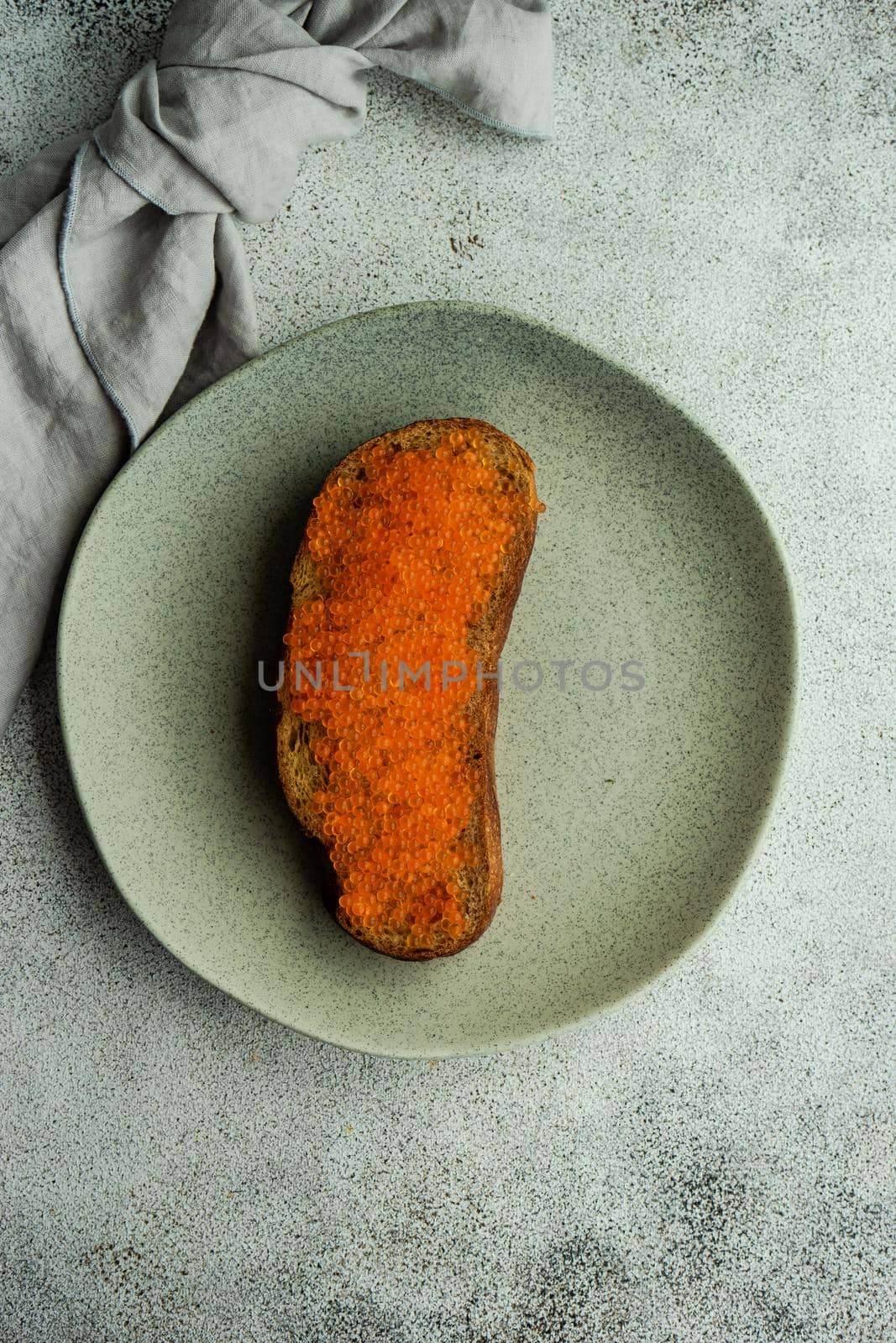 Wholegrain bread toasts with red trout caviar served on stoneware plate