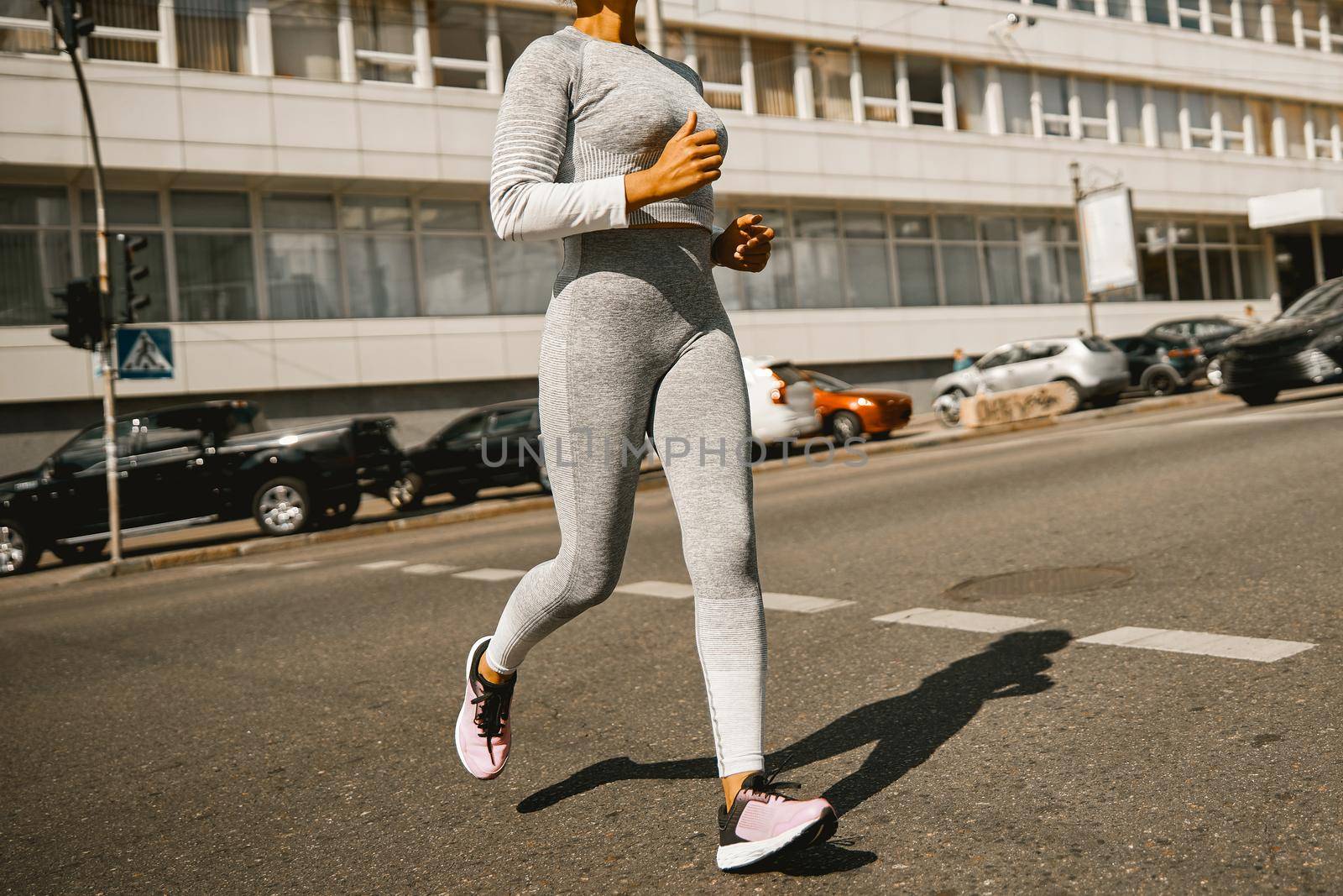 Cropped shot of sporty woman in gray sportswear running in the city. Sports, active lifestyle