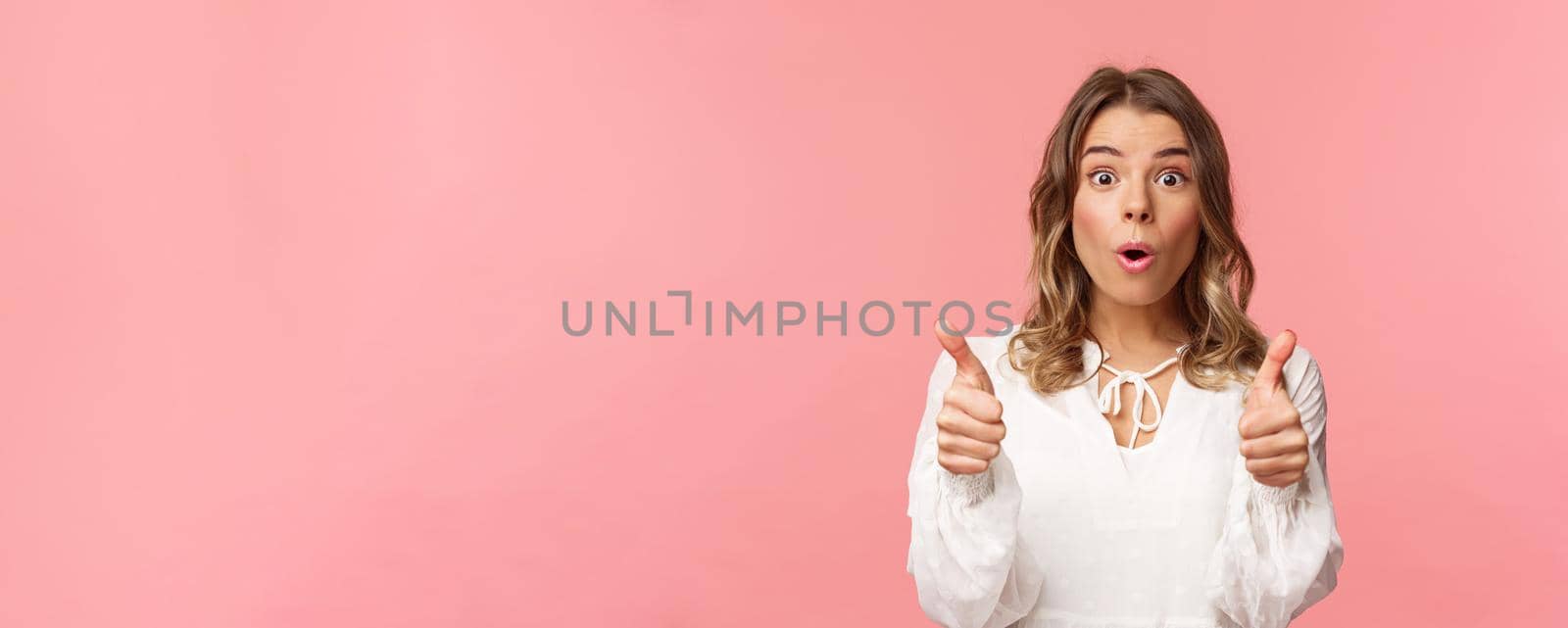Close-up portrait of impressed blond girl showing thumbs-up look astonished and disbelief as processing fascinating performance she saw, leave positive review, standing pink background by Benzoix