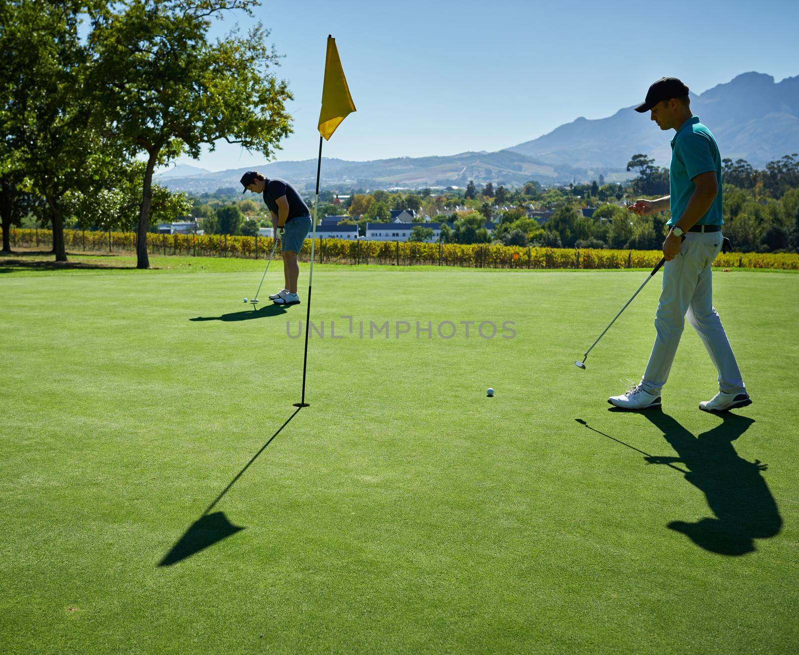 Putting the whole day. Shot of two focused young men playing a game of golf outside on a golf course. by YuriArcurs
