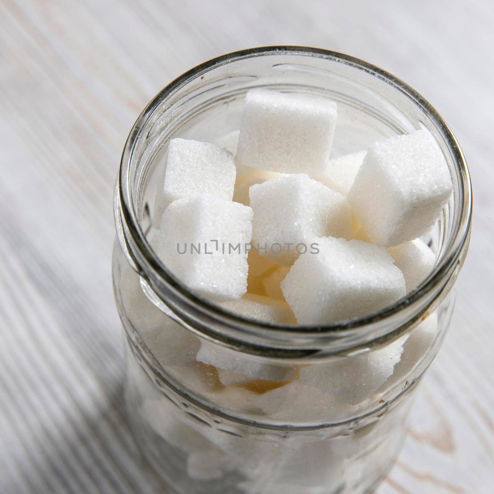 Glass jar with refined sugar in pieces by elenarostunova