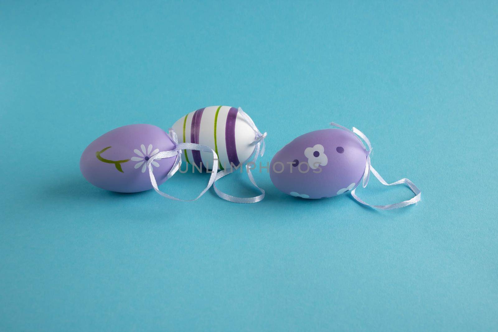 Three painted eggs lie on a blue background. lilac easter eggs easter concept.
