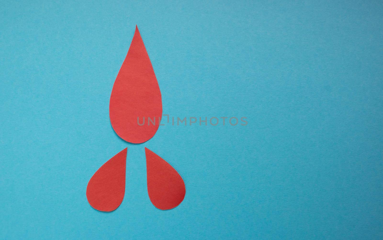 The concept of the World Blood Donor and Hemophilia Day. Red paper drops of blood on a blue background by lapushka62