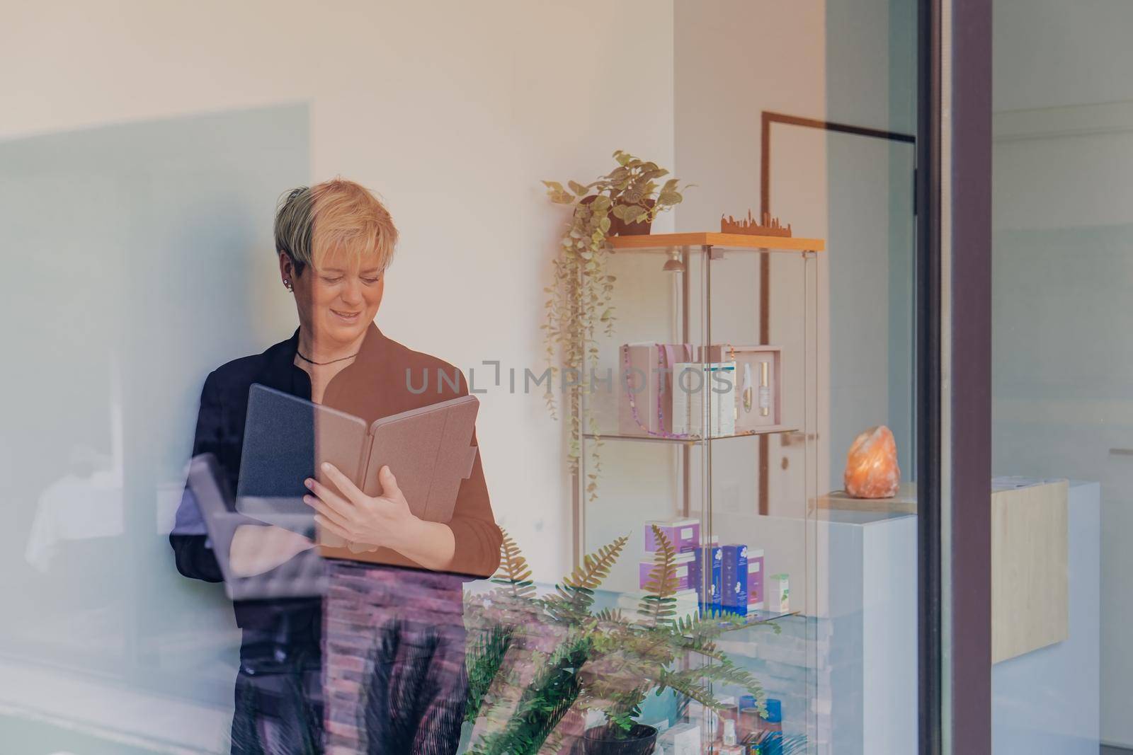 portrait through a window of a business woman checking work tasks on her Tablet. entrepreneurial woman. by CatPhotography