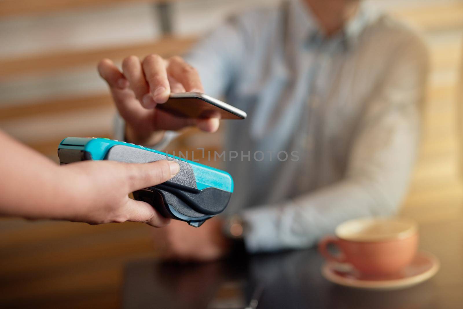 Shot of a man making a payment with his cellphone using NFC technology in a cafe.