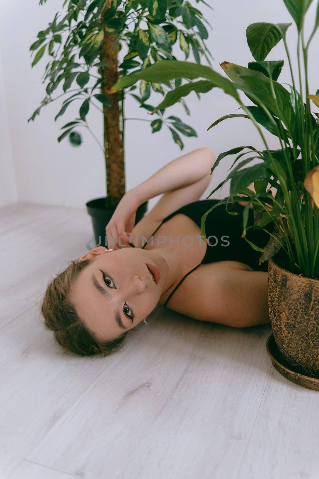 Portrait of young caucasian woman in red cloth laying near flowerpot. Dreamy