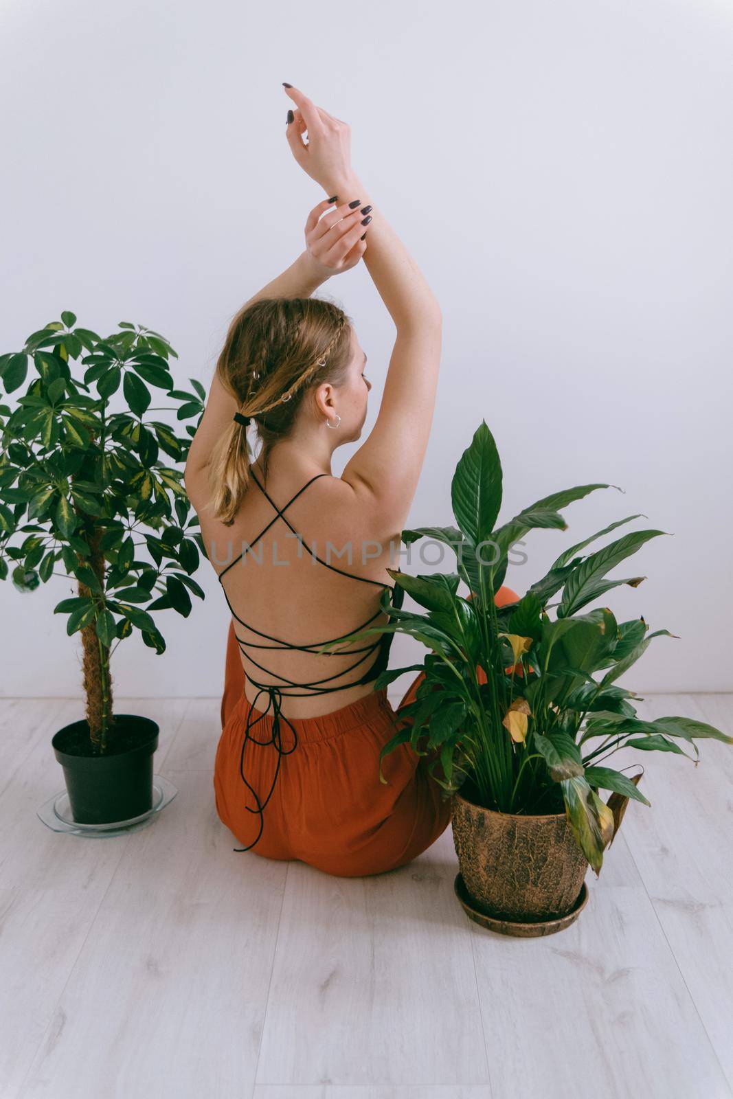 Portrait of young caucasian woman in red cloth sitting near flowerpot rear view. Dreamy