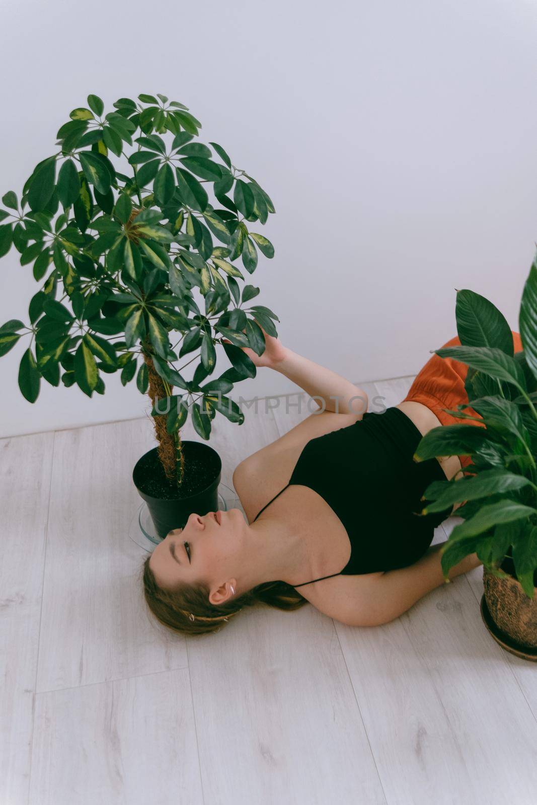 Portrait of young caucasian woman in red cloth laying near flowerpot. Dreamy