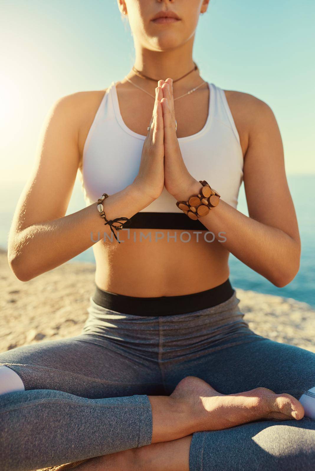 Shot of a young woman doing yoga at the beach.