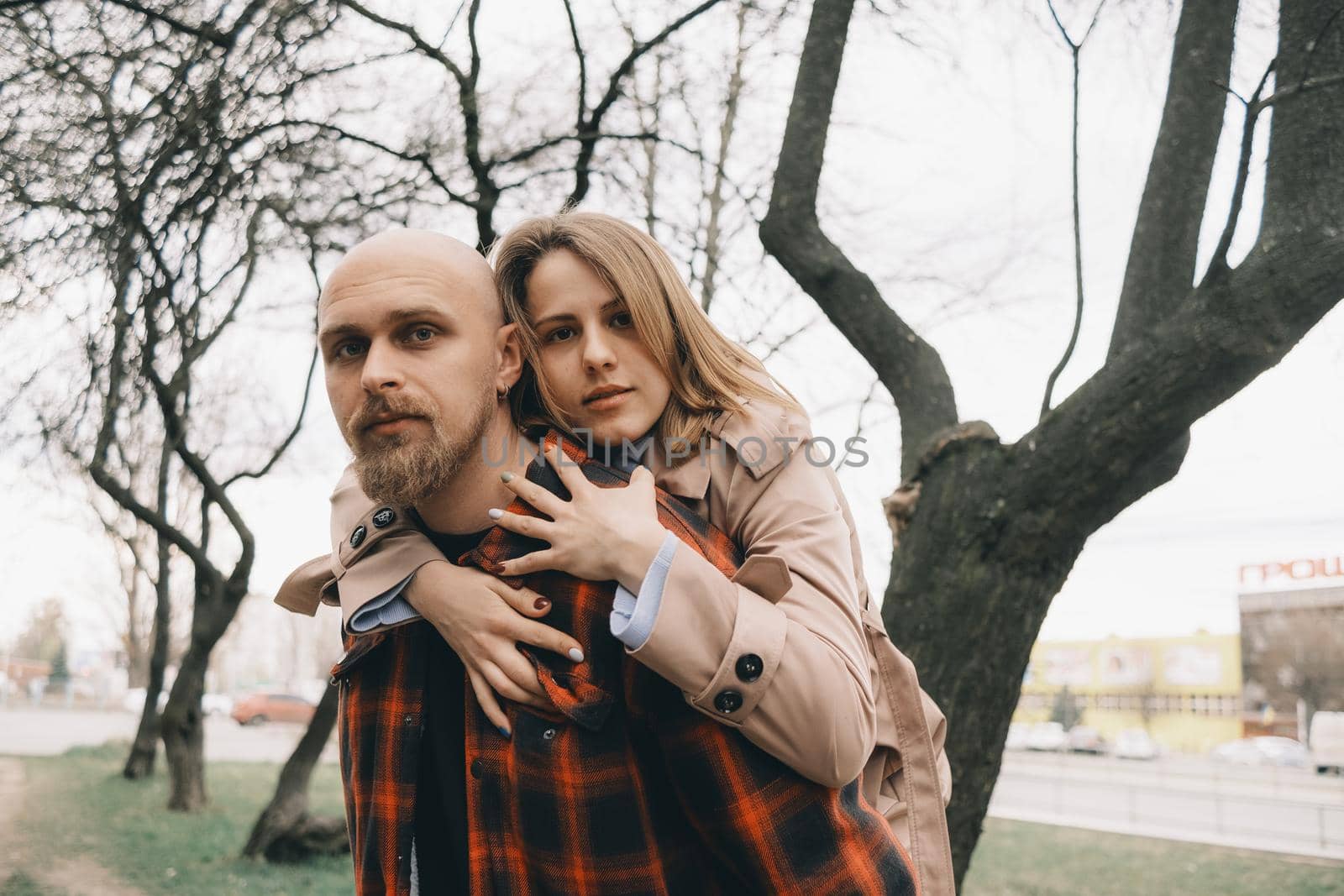 Loving couple embrace with each other. Tree on background. Hipster