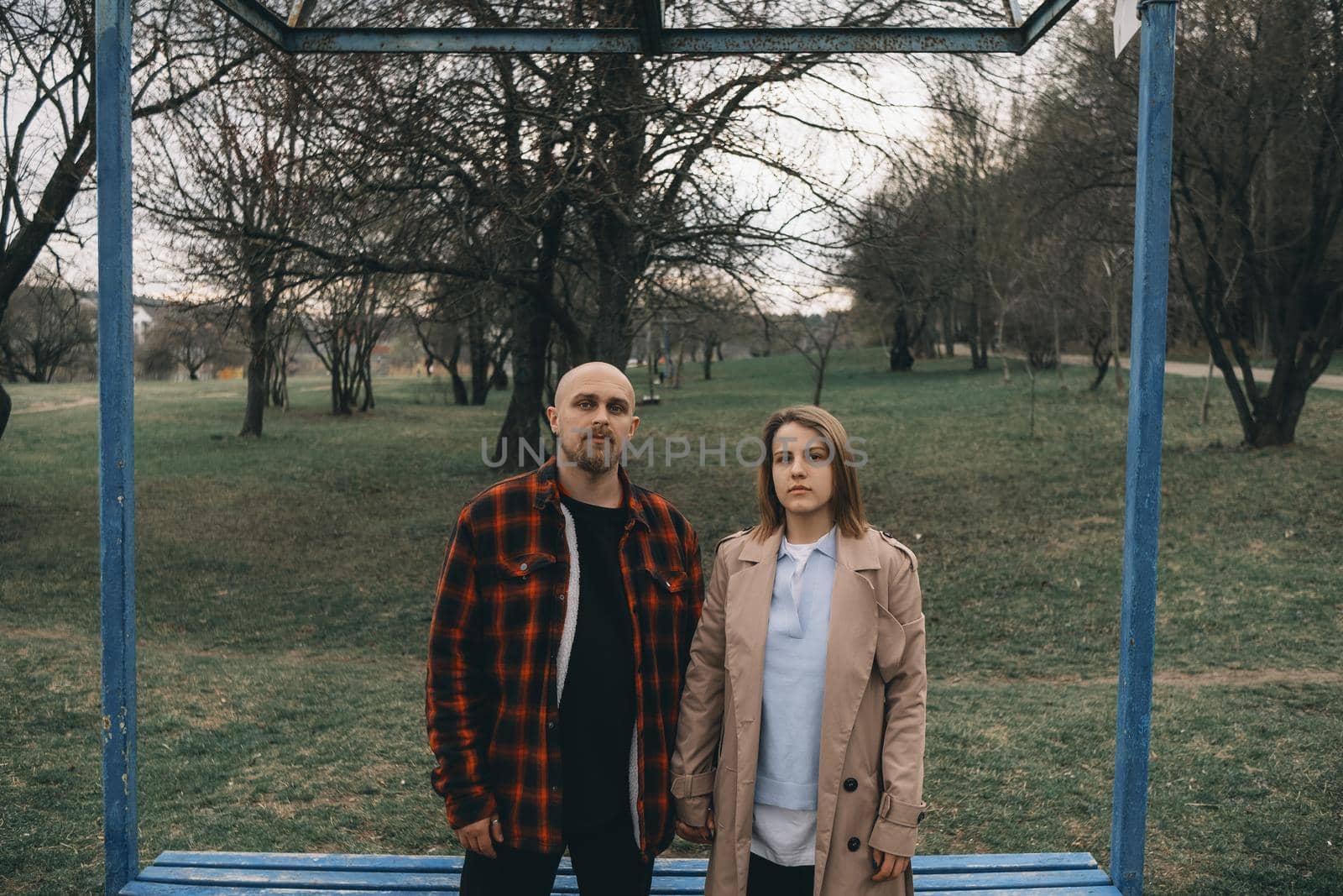 Portrait of a young white couple looking at the camera with suspicion. Outdoors