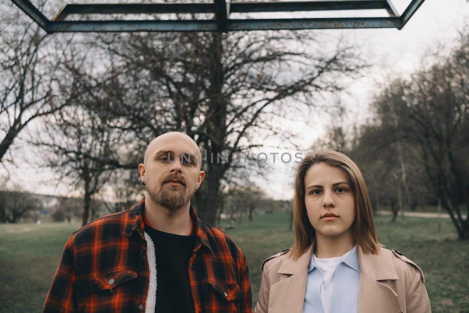 Portrait of a young white couple looking at the camera with suspicion. Outdoors