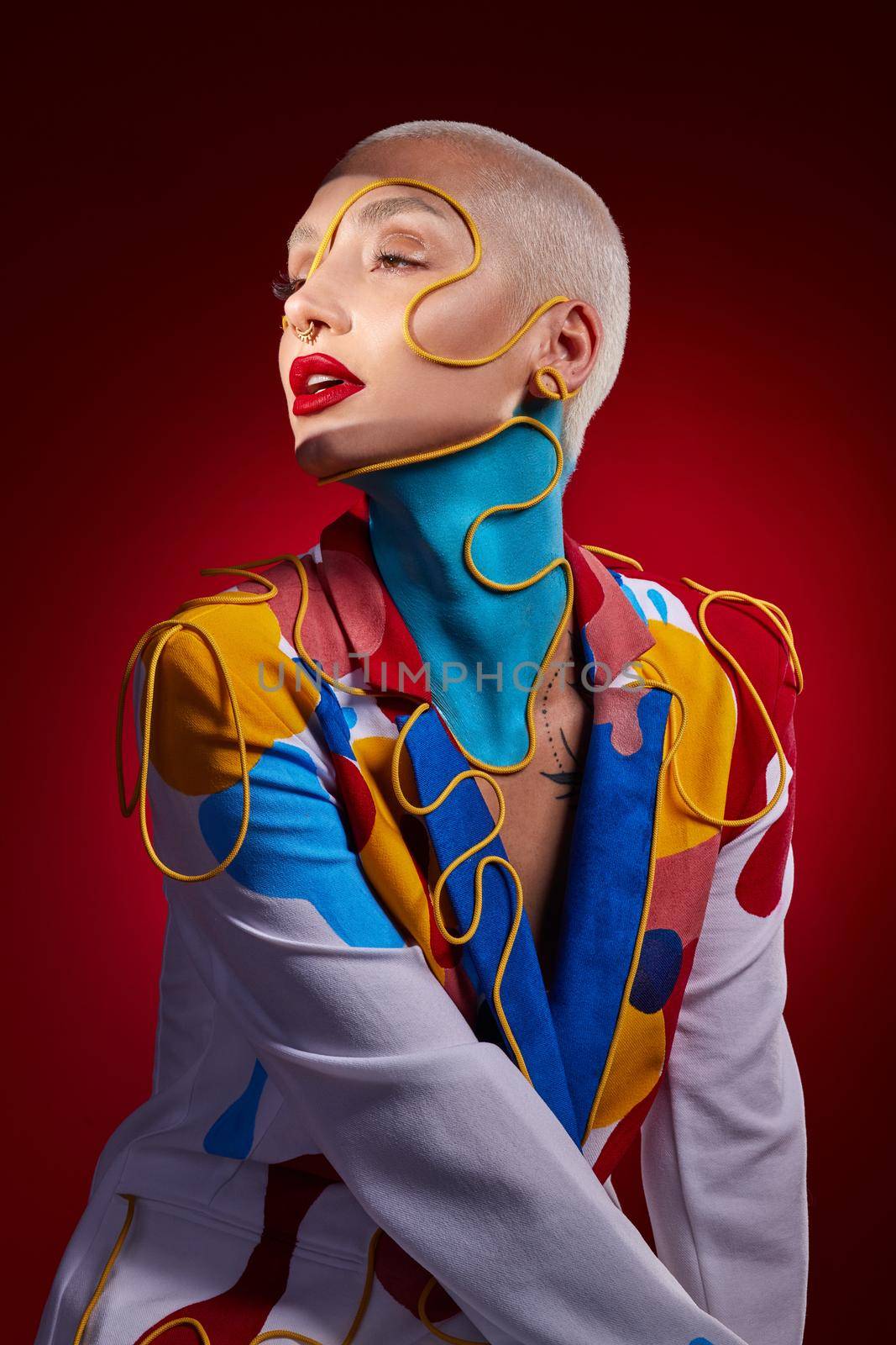 Studio shot of a stylish young woman posing against a red background.