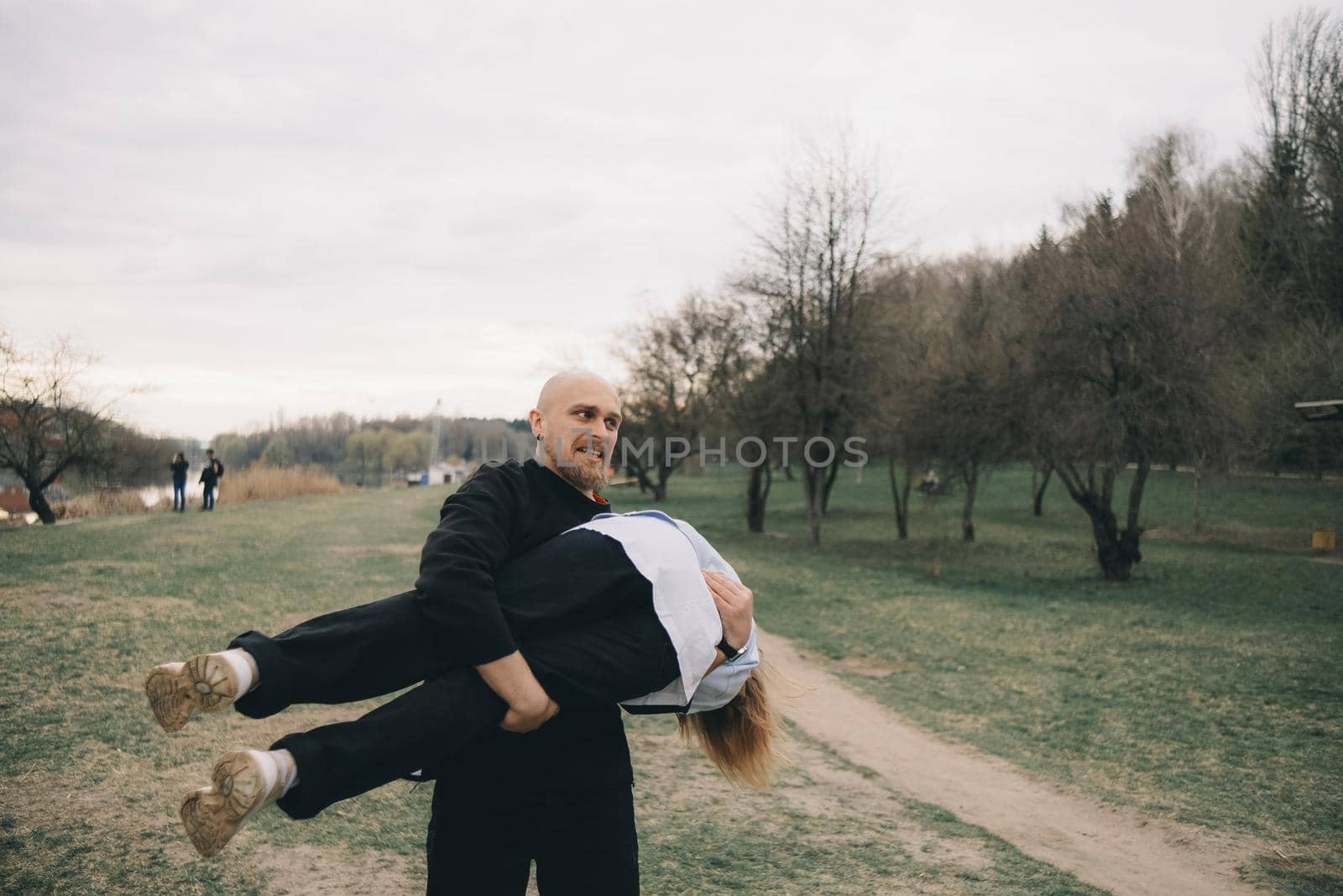 man carries a woman in his arms in the park and they have fun and happy