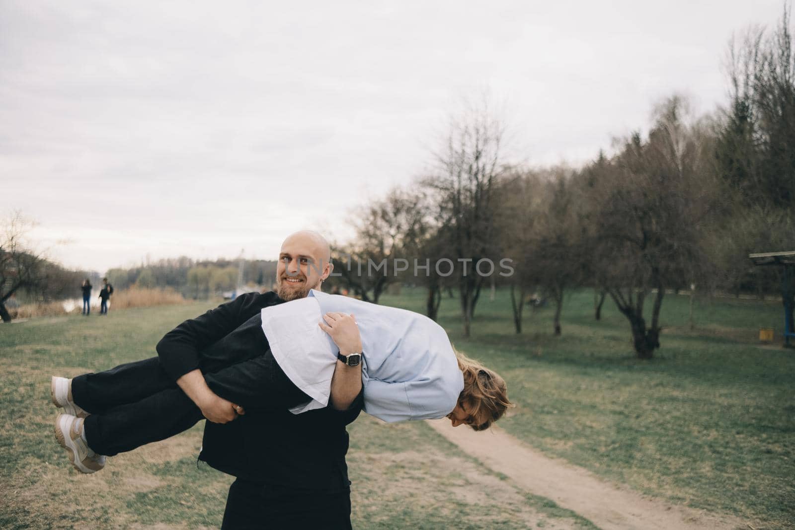 man carries a woman in his arms in the park and they have fun and happy