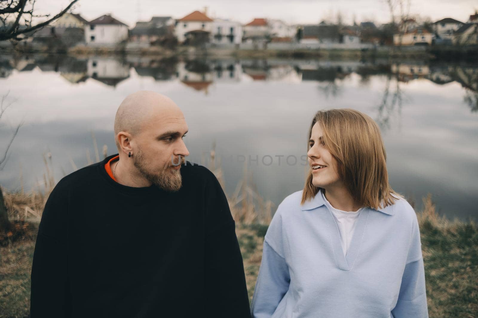 Portrait of a young white couple looking on each other with suspicion. Outdoors