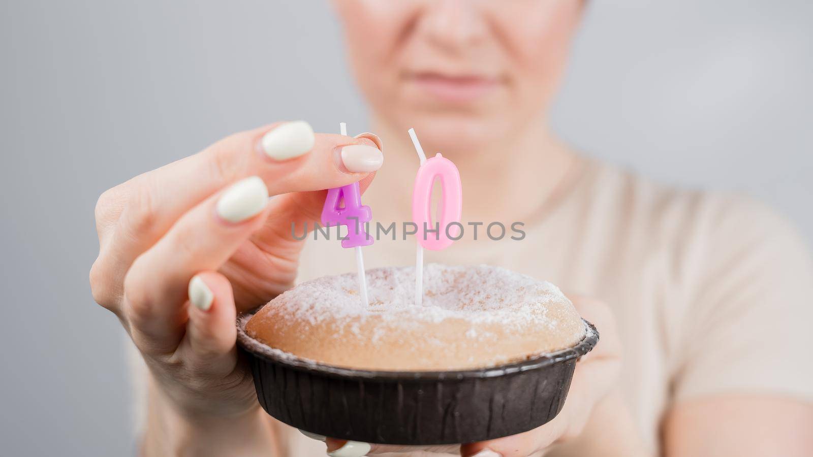Unhappy woman holding a cake with candles for her 40th birthday. The girl cries about the loss of youth