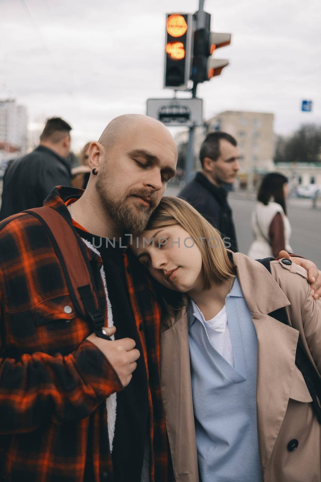 loving couple standing wearily in the arms of the city ith eyes clossed